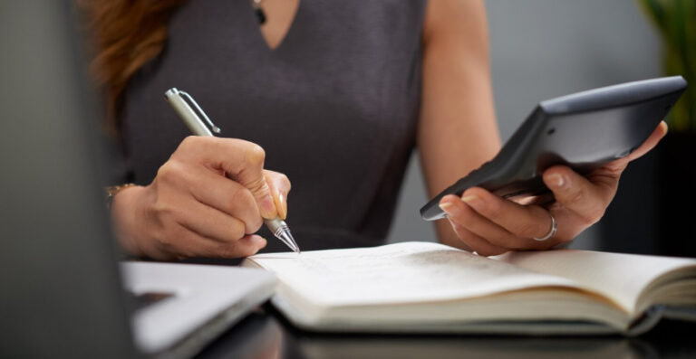 Empresa fatura bem mas não sobra dinheiro — empresária analisando contas com calculadora e caderno