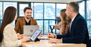 Distribuição de lucros como fazer certo — sócios reunidos em mesa de reunião com laptop e tablet discutindo resultados