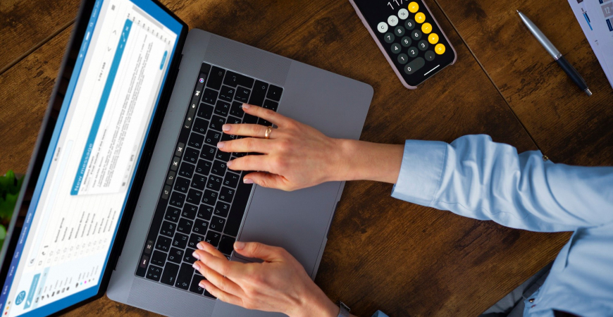 Planejar em julho salva seu caixa — profissional digitando no laptop com calculadora ao lado para provisionar o 13º salário