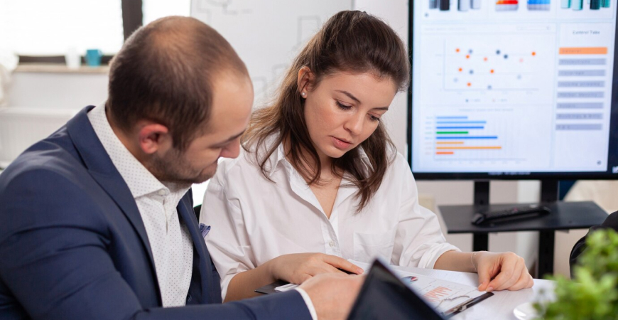 Inadimplência de clientes como proteger o caixa — dois profissionais analisando relatório financeiro com gráficos ao fundo
