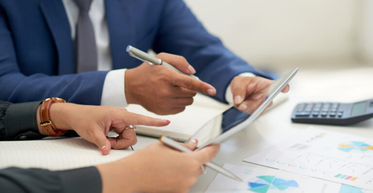 Balanço patrimonial fechamento de ano — contador e empresário analisando documentos com gráficos e tablet em reunião de revisão contábil