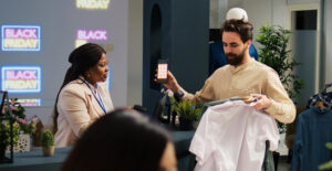 Black Friday no comércio do ABC — vendedora mostrando produto e maquininha para cliente em loja decorada com letreiros da Black Friday